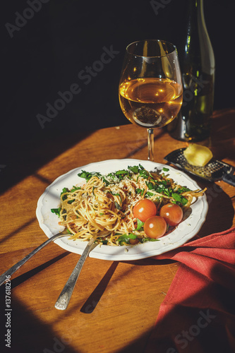 Spaghetti with cherry tomartoes served on a wooden table.