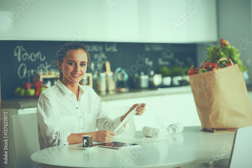 Young woman planning expenses and paying bills on her kitchen
