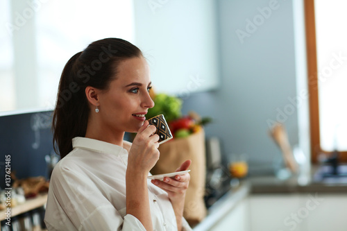 Happy woman drinking tea in the kitchen at home