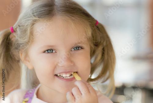 Little girl is eating chips. Portrait of baby has lunch. 