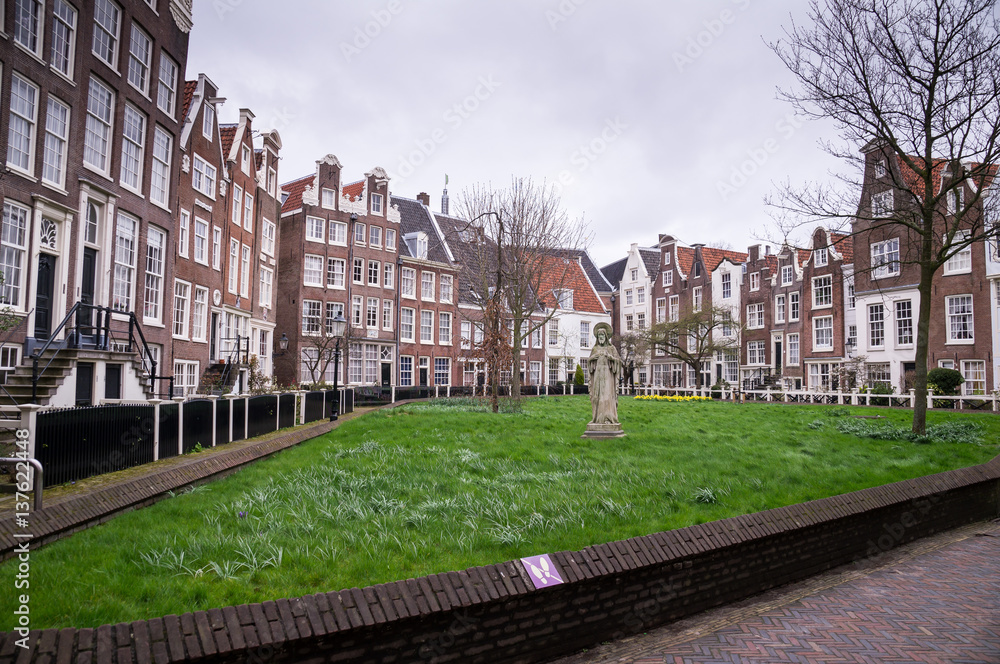 Old Dutch buildings of the Begijnhof surrounded by a park in Amsterdam, Netherlands