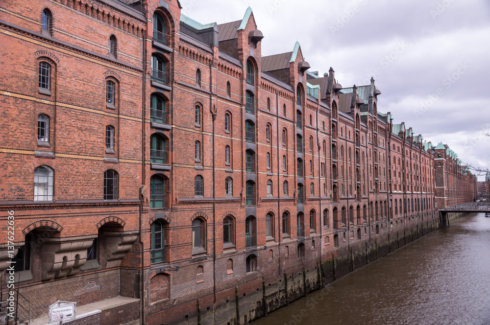 Tourist boat in famous Speicherstadt warehouse district with brick houses in Hamburg, Germany