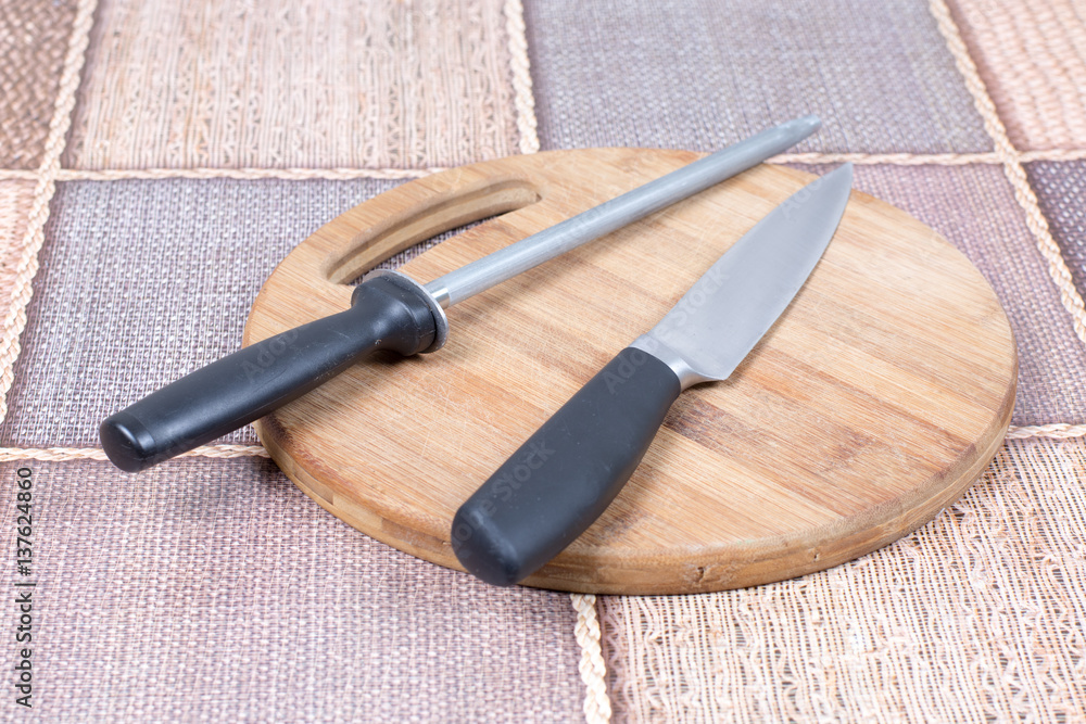 Kitchen knife with knife sharpener tool on the kitchen wooden board