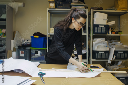 female fashion desighner draws dress template on panel table in workshop interior photo