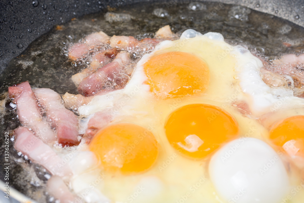 Frying eggs with sliced bacon in the hot oil Frying eggs with sliced bacon in the hot oil