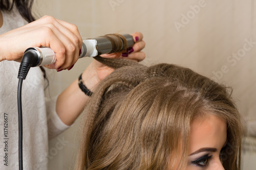 Barber stylist makes a girl hairstyle at beauty salon