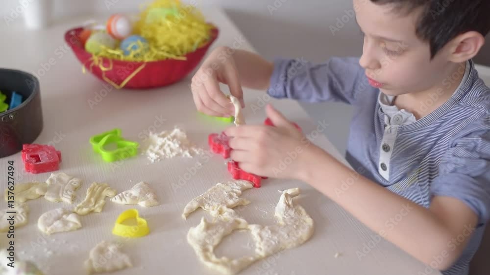 Boy preparing cakes for Easter.Young boy playing with dough at home Boy preparing cakes for Easter.Young boy playing with dough at home