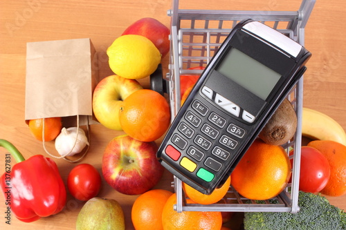 Payment terminal with fruits and vegetables, cashless paying for shopping, finance concept