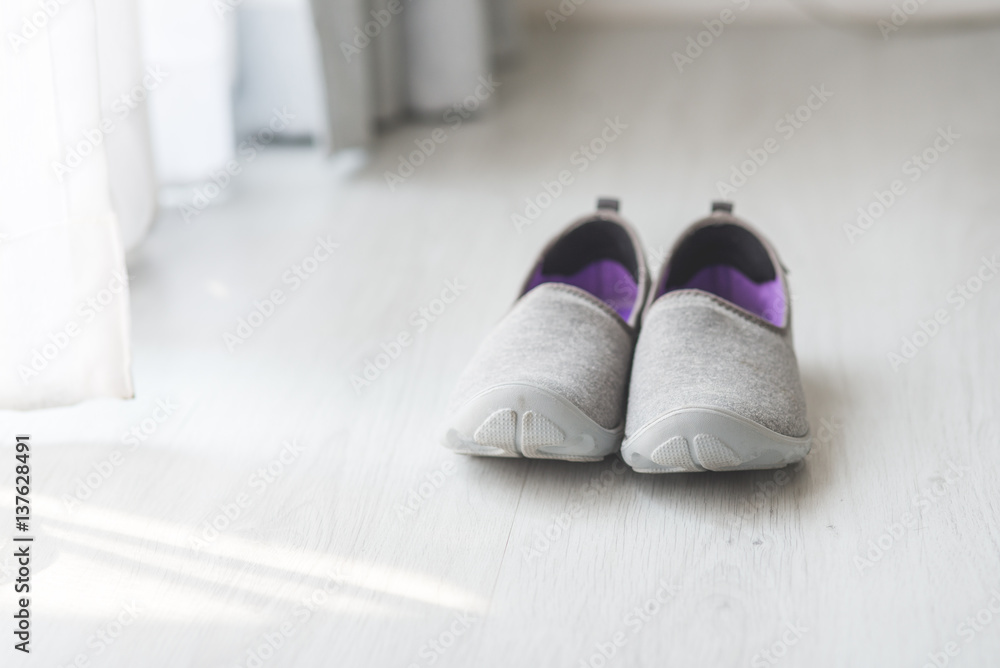 Gray, purple fabric shoes beside view for walking on wooden gray floor Gray, purple fabric shoes beside view for walking on wooden gray floor