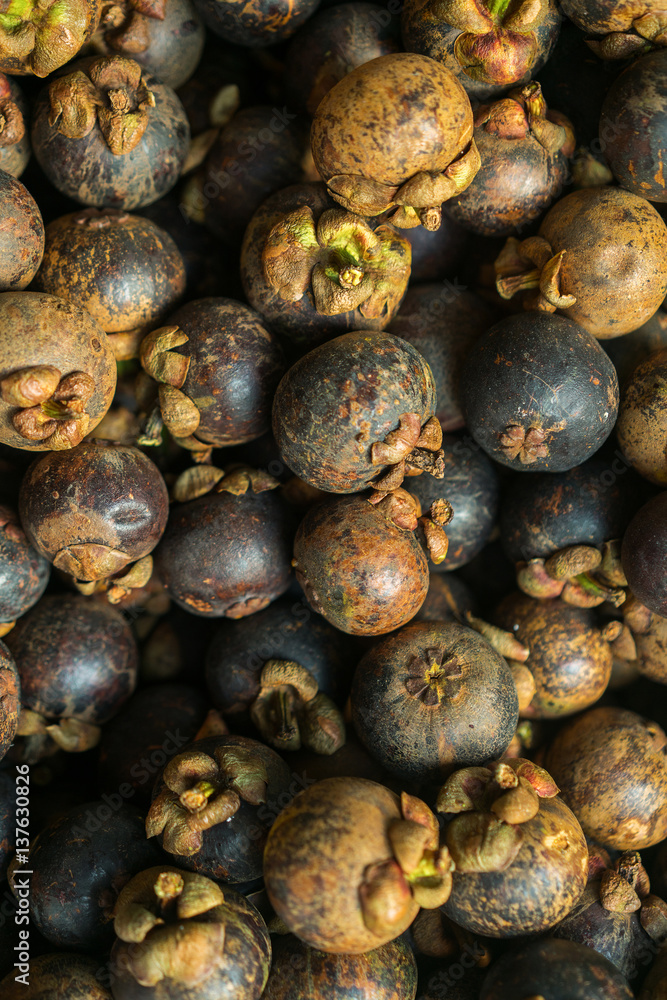 The mangosteen fruit lying on the market. Background many mangosteen fruit. The mangosteen fruit lying on the market. Background many mangosteen fruit.