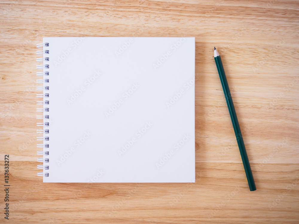 white cover notebook top view with pencil on brown wood desk