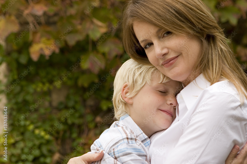 Happy mother hugging her son outside.