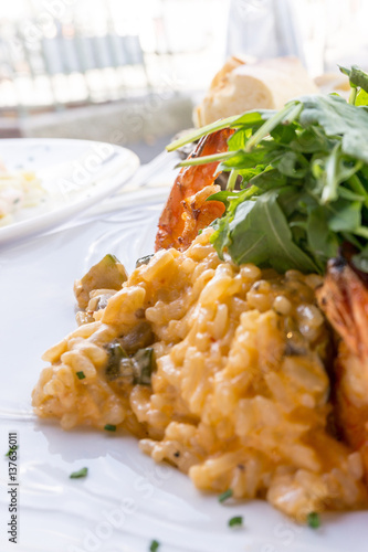 Tasty risotto with Shrimp, fresh herbs vegetables on a white plate