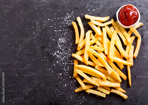 Fotografiet French fries with ketchup on dark table