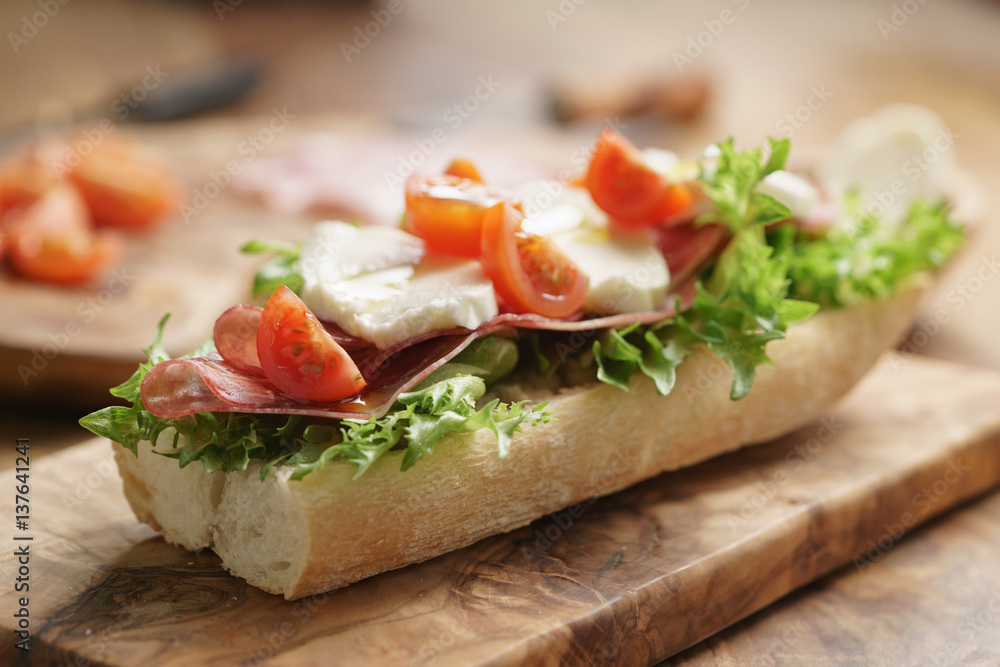 open sandwich with prosciutto, mozzarella and tomatoes on kitchen table open sandwich with prosciutto, mozzarella and tomatoes on kitchen table