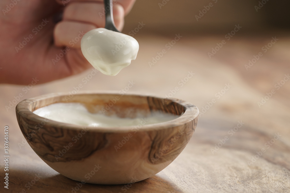 eating with spoon homemade organic yogurt in wooden bowl on table eating with spoon homemade organic yogurt in wooden bowl on table