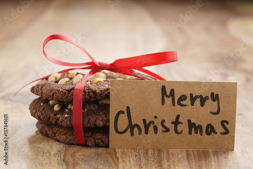 stack of homemade chocolate cookies with hazelnuts tied with ribbon on wood table and paper card