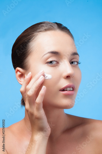 Jeune femme applique de la crème hydratante sur son visage photo