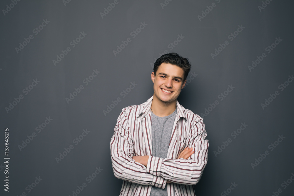 Happy cheerful guy with crossed hands on gray background