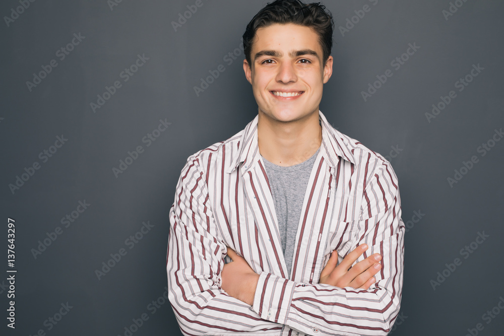 Obraz premium Happy cheerful guy with crossed hands on gray background