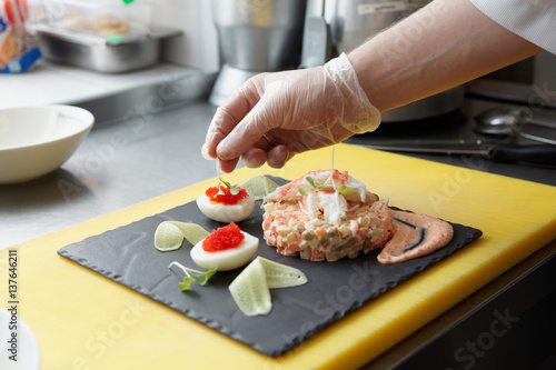 Chef is decorating crab salad in commercial kitchen