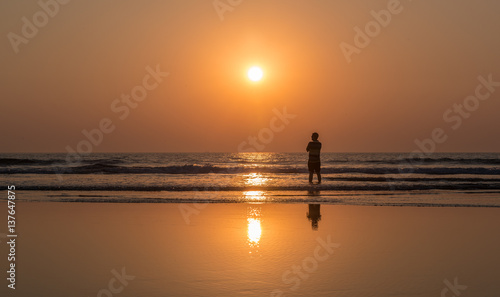 the person against the background of a sunset and the ocean