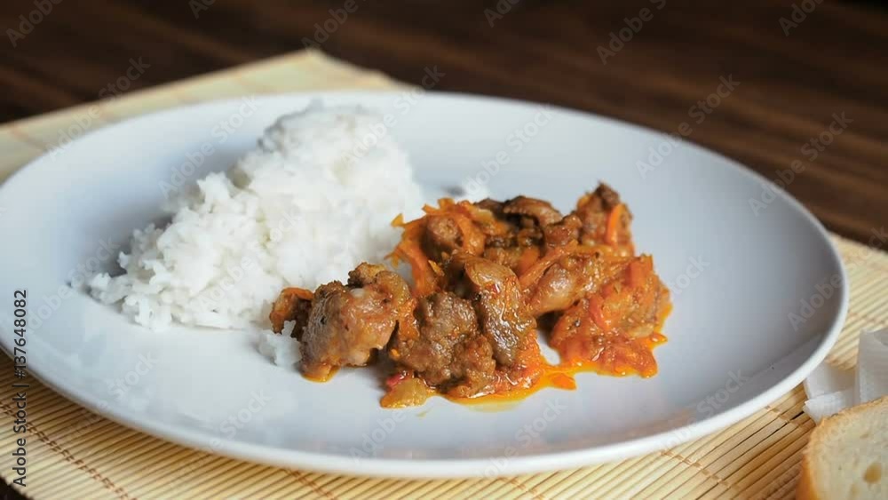 Plate of fresh, steaming rice. Static scene with snow white ceramic dish of rice and roast meat, stew, meats with vegetables on a bamboo napkin on a wooden table from the old boards. Plate of fresh, steaming rice. Static scene with snow white ceramic dish of rice and roast meat, stew, meats with vegetables on a bamboo napkin on a wooden table from the old boards.