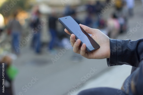 Side close up view of a man using the mobile phone in a turistic atmosphere