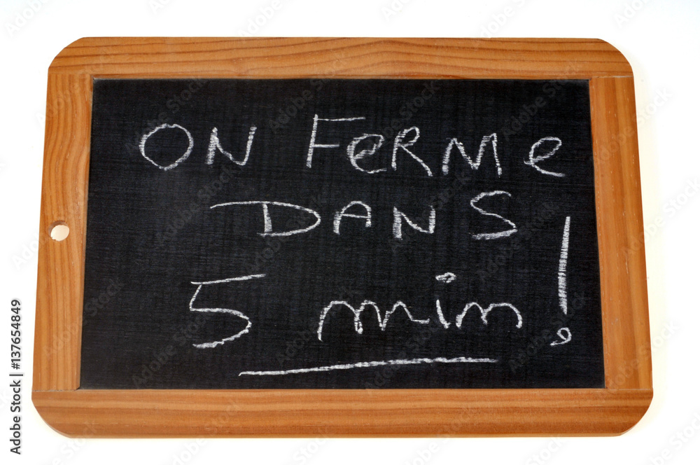 On ferme dans cinq minutes écrit sur une ardoise On ferme dans cinq minutes écrit sur une ardoise