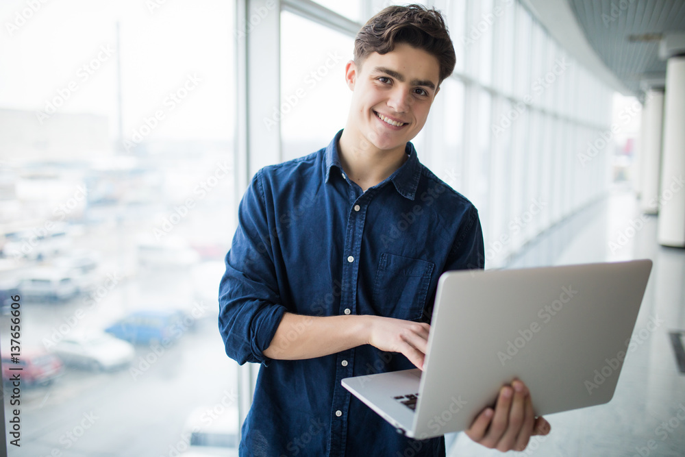 Handsome young man man holding a laptop in hall Handsome young man man holding a laptop in hall