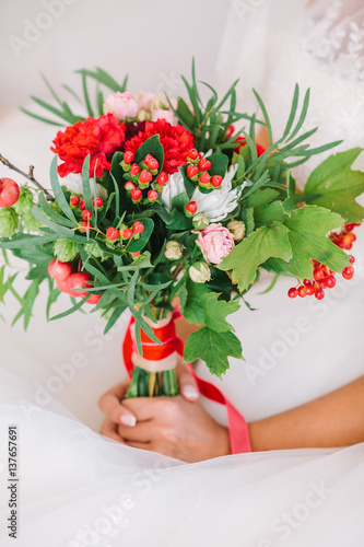 Fototapeta Naklejka Na Ścianę i Meble -  Beautiful woman in a white wedding dress holding a flowers bouquet in hand. Wedding bridal bouquet on a white background.