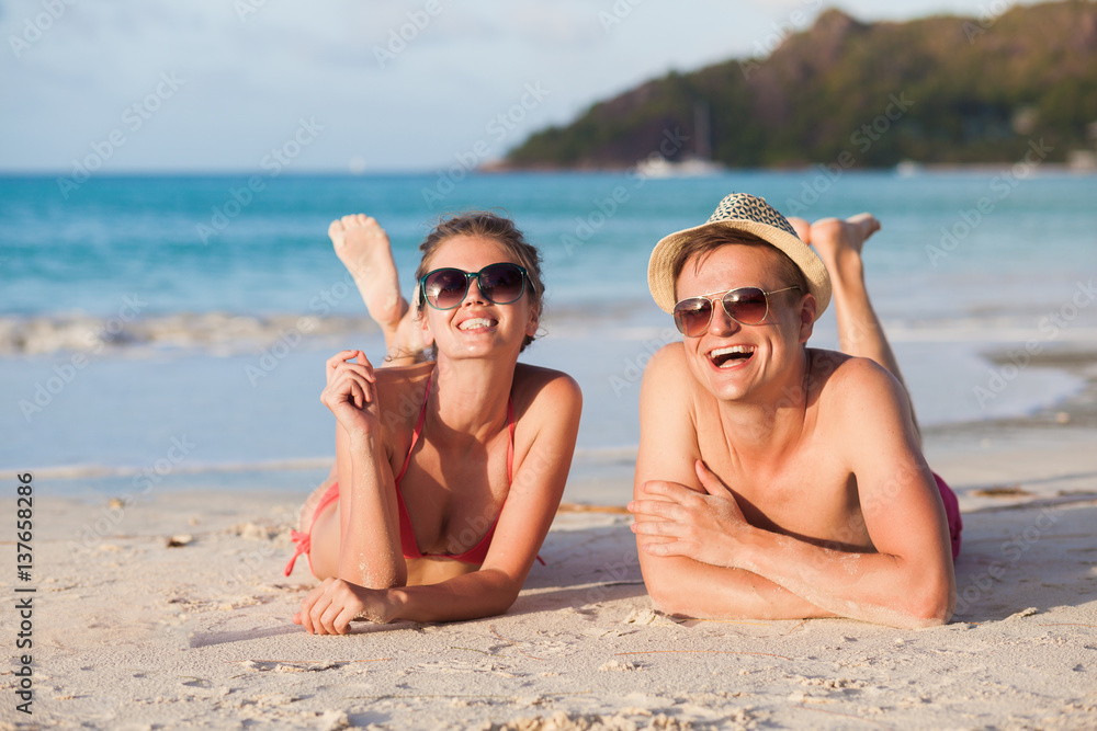 happy young couple lying and having fun on a tropical beach