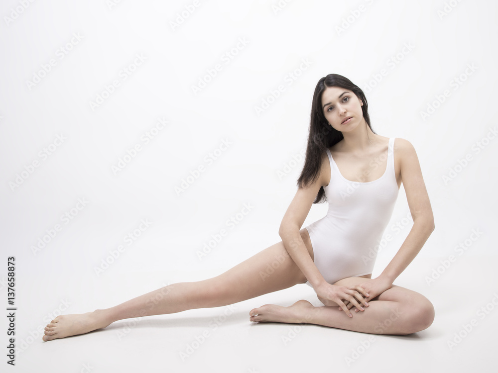 Brunette model sitting on the white floor full length Brunette model sitting on the white floor full length