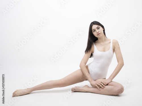 Brunette model sitting on the white floor full length