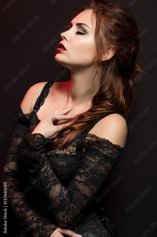 Young woman in black gothic costume on dark background Young woman in black gothic costume on dark background