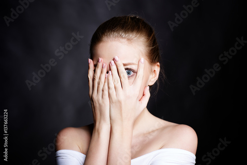Scared girl covering her face with her hands