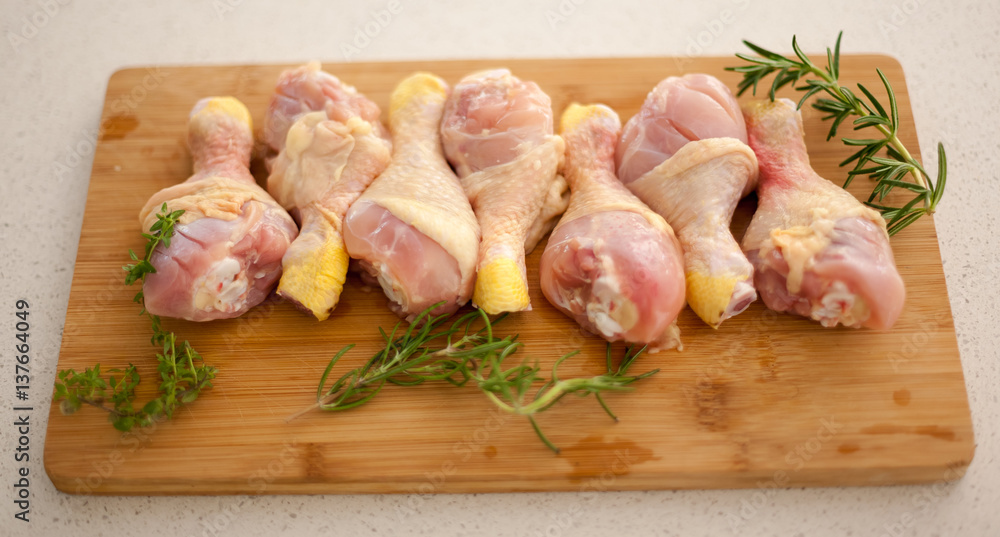 Chicken drumsticks on a cutting board with fresh rosemary and thyme. Chicken drumsticks on a cutting board with fresh rosemary and thyme.