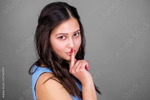 Young beautiful woman has put forefinger to lips as sign of silence