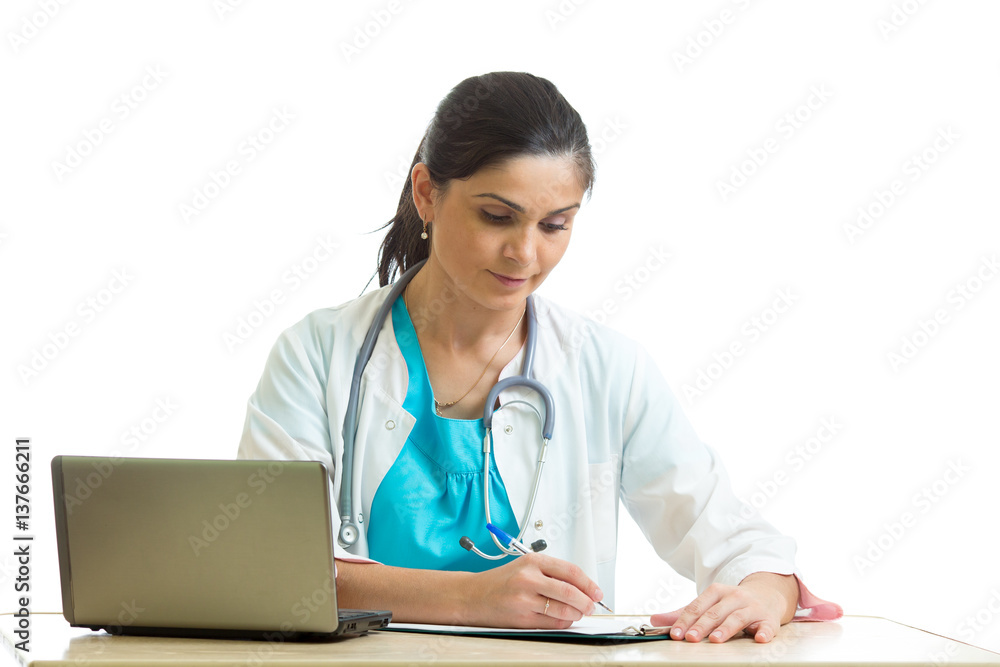 Beautiful female doctor sitting at the table and writing. Isolated on white background Beautiful female doctor sitting at the table and writing. Isolated on white background