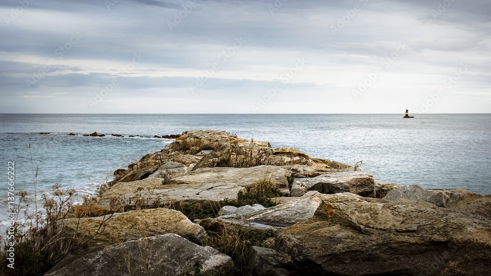 Camino de rocas en el mar y faro en el horizonte