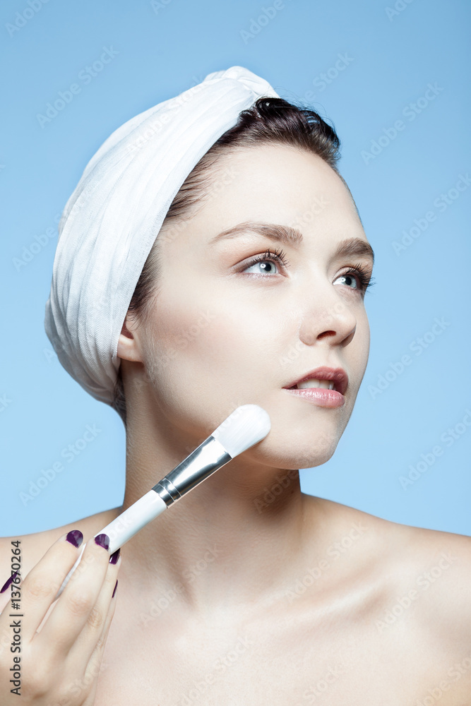 Portrait d'une femme en utilisant une brosse de maquillage sur le visage