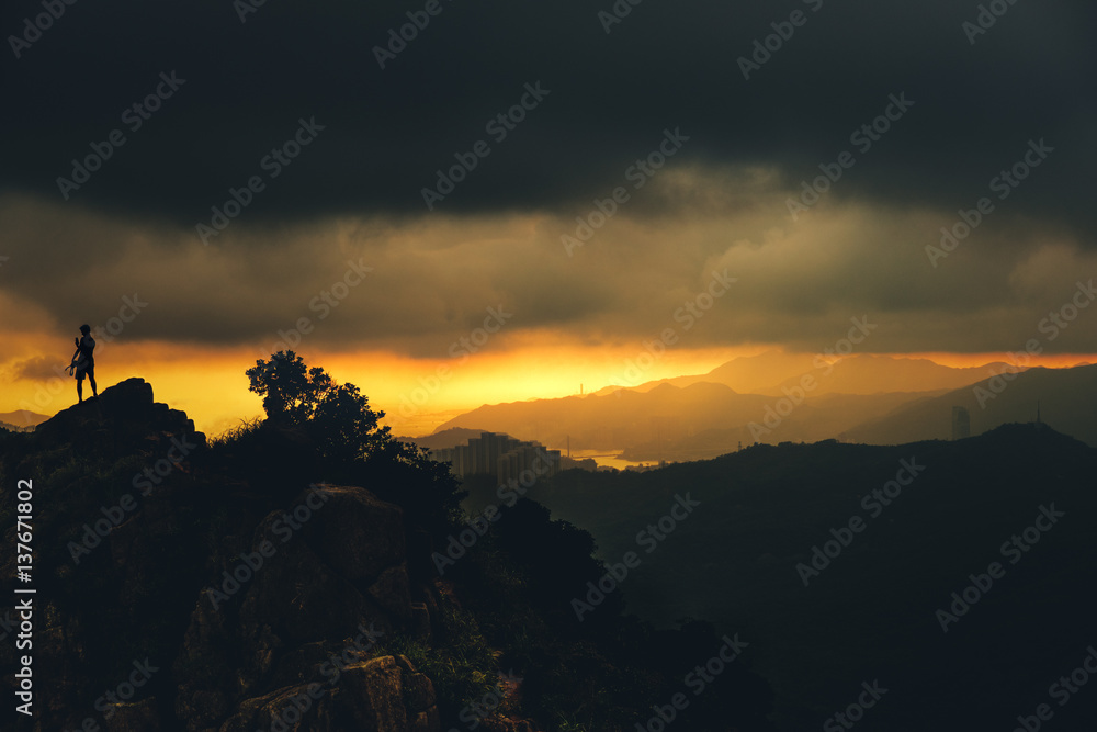 Obraz premium Landscape with silhouette of a standing men take a photo withn phone on lionrock peak in hongkong.