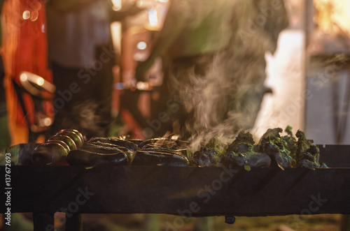 Grilling a delicious shashlik with smoke marinated meat and tomato at night time © zef art