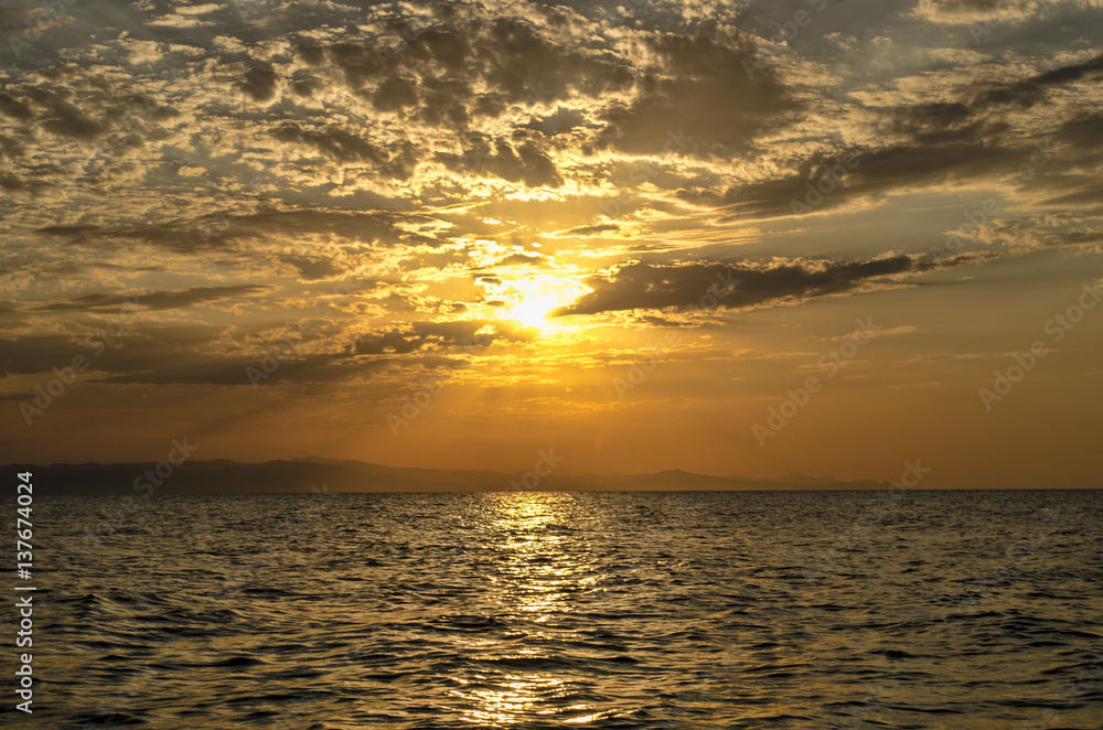 Obraz premium Beautiful blazing sunset landscape at Caspian sea and orange sky above it with awesome sun golden reflection on calm waves as a background. Amazing sunset view on the beach. Azerbaijan Absheron, Baku