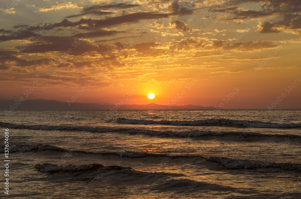 Beautiful blazing sunset landscape at Caspian sea and orange sky above it with awesome sun golden reflection on calm waves as a background. Amazing sunset view on the beach. Azerbaijan Absheron, Baku