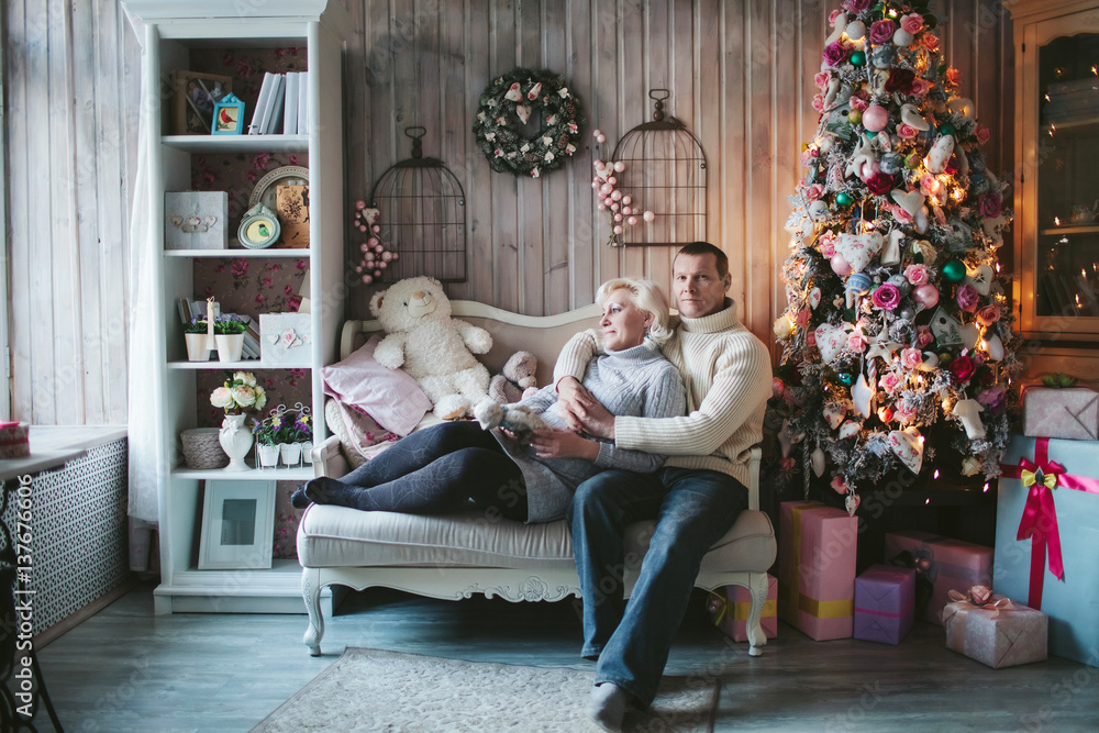 Obraz premium adult couple sitting at the Christmas tree