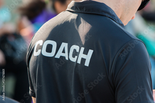 Photo back of a coach's black color shirt with the word Coach written on