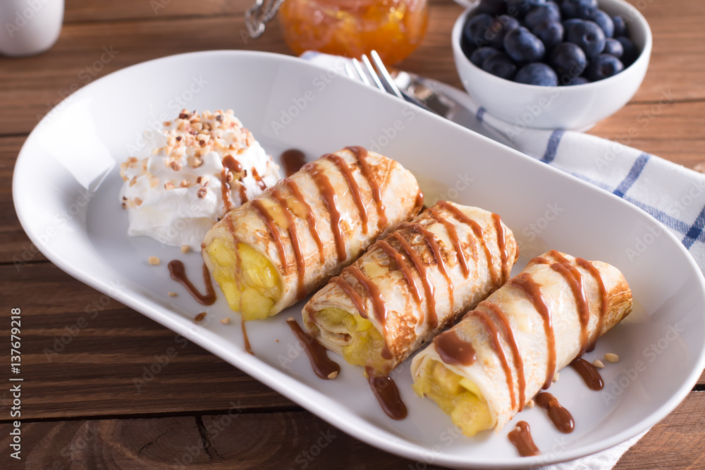 Pancakes with Apple and caramel sauce,whipped cream, served on a white plate on a wooden table. Selective focus Pancakes with Apple and caramel sauce,whipped cream, served on a white plate on a wooden table. Selective focus