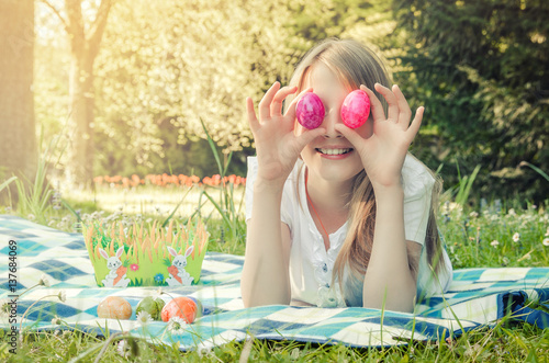 cheerful positive girl holding colorful Easter eggs and posing in Park outdoors