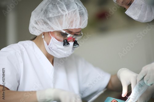 Dentist and assistant are using surgical thread and tools necessary for the manipulation photo